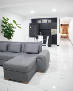 a living room with a gray couch and a kitchen at El REFUGIO DEL SOL CASA TURISTICA in Calarcá