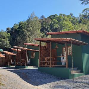 a small green house with trees in the background at Pousada do Coura in Pouso Alto