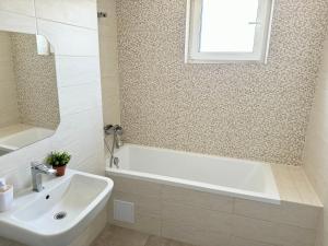 トゥルグ・ムレシュにあるMilan Luxury Apartaments V-Maurer Residenceの浴槽と洗面台と窓のあるバスルーム