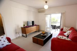 a living room with a red couch and a tv at The Love Nest in Pissouri