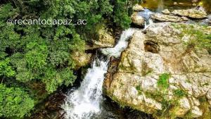 Antônio CarlosSuíte com cachoeira no quintal的岩石山边的瀑布