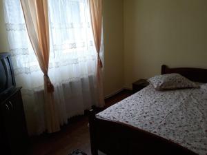 a bedroom with a bed and a window with curtains at Cabana Claudia Briciu in Arieşeni
