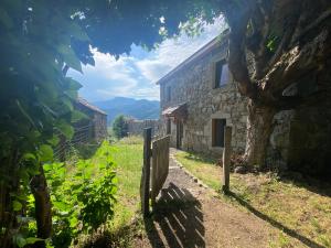 una casa de piedra con una valla y un árbol en Gîte de charme en plein cœur de l’Ardèche verte, en La Rochette