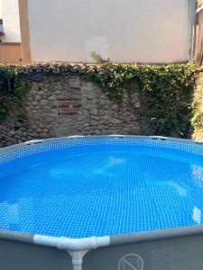a blue swimming pool in front of a stone wall at La Posada De Alanah in Candeleda