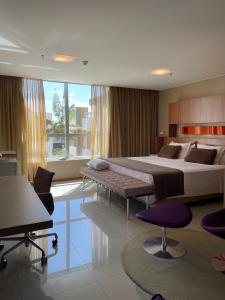 ブラジリアにあるJade Hotel Condomínio suite particular super kingのベッドルーム1室(大型ベッド1台、テーブル、椅子付)