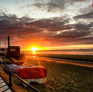 a bed on a beach with the sunset in the background at Tranquility at Sandown Bay in Sandown