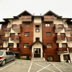 ein Mehrfamilienhaus mit einem auf einem Parkplatz geparkten Auto in der Unterkunft Jekaa in Zlatibor