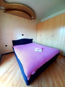 een slaapkamer met een groot bed met een paars dekbed bij Apartman San in Bajina Bašta