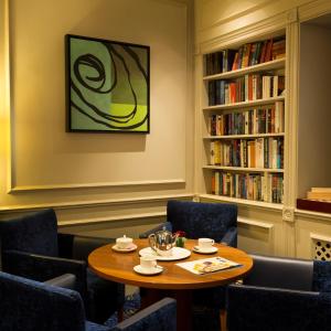 a room with a table and chairs and bookshelves at Somerville Hotel in Saint Aubin