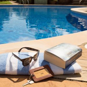 a book and glasses on a towel next to a swimming pool at Somerville Hotel in Saint Aubin