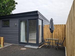 a black tiny house with a table and an umbrella at Moira Garden Tiny Home in Moira