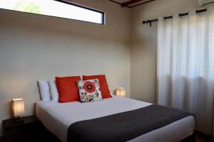 a bedroom with a bed with red pillows and a window at Villa Victoria, Valle de Guadalupe in Valle de Guadalupe
