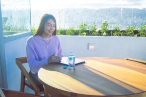 a woman sitting at a table with a bottle of water at Hermoso Penthouse Vistas Espectacular in Quito