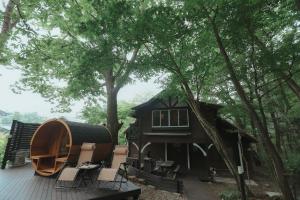 eine Hütte im Wald mit einer Terrasse und Stühlen in der Unterkunft NASU terrace MANA 森のバレルサウナとBBQグリル in Nasu