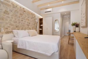 科孚镇Celestial Suites-TOP LOCATION的卧室配有白色的床和石墙