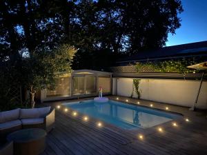 a swimming pool with lights in a backyard at night at Cosy Villa Arcachon Bay in Audenge