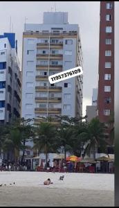 a person and a dog on the beach with a building at Apartamento mobiliado prédio frente ao mar in São Vicente