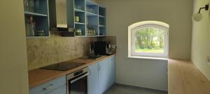 a kitchen with white cabinets and a window at Vila Pakaso malūnas in Kirdeikiai