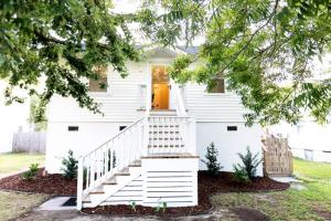 a white house with stairs in front of it at NEW! 1937 Coastal Cottage by Beach, Boardwalk, & Lake! in Carolina Beach