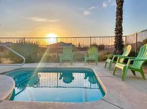 a swimming pool with chairs and a sunset in the background at North Shore Inn at Lake Mead in Moapa Valley