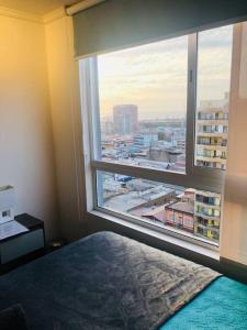 a bedroom with a large window with a view of a city at Hermoso departamento con vista al mar pleno centro in Antofagasta