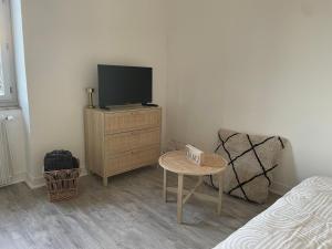 a bedroom with a tv and a chair and a table at La parenthèse dorée Studio à saint bel in Sain-Bel