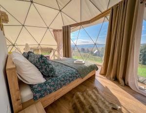 a bed in a tent with a large window at Durmitor Glamp in Žabljak