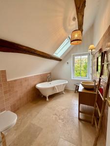 ein Badezimmer mit Badewanne und Toilette und einem Fenster in der Unterkunft Maison de campagne proche de Paris in Vienne-en-Arthies
