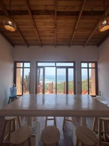 a large table with chairs in a room with windows at Cabana Alegria - Ocean View Home - 2 Master Suites in San Agustinillo