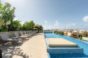 a hotel swimming pool with lounge chairs on the roof at Tu Oasis en Playa del Carmen in Playa del Carmen