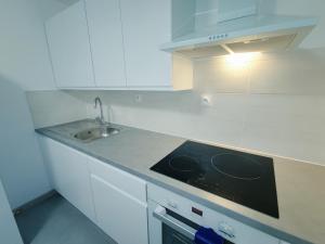 a kitchen with white cabinets and a stove and a sink at La Suite Élégance in Obernai +8 photos
