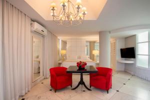 a room with a table and two red chairs and a bed at Suntory Hotel in Pará de Minas +25 photos