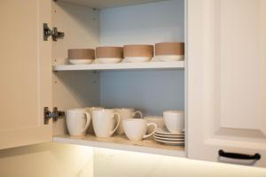a cupboard with cups and plates in it at Apartman Mila Subotica in Subotica +36 photos