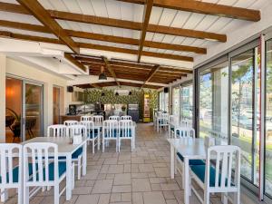 a restaurant with white tables and chairs and windows at Akpınar Marin Hotel in Çeşme