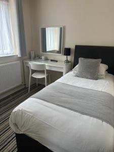 a bedroom with a white bed and a desk at Alder Lodge in Cambridge +3 photos