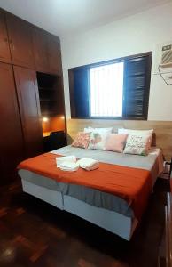 a bedroom with a large bed with an orange blanket at Casa espaçosa pertinho da praia in Santos