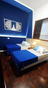 two beds in a room with blue walls at Casa espaçosa pertinho da praia in Santos
