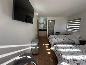 a room with two beds and a flat screen tv at TinyApartments - estudio pleno centro Concepción in Concepción