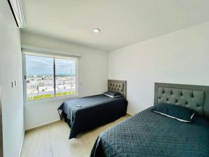 ein Schlafzimmer mit zwei Betten und einem Fenster in der Unterkunft cómodo con alberca cerca de la playa by G P S rentas in Mazatlán + 15 Fotos