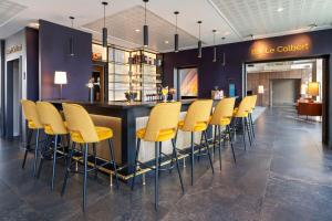 eine Bar mit gelben Barhockern in einem Restaurant in der Unterkunft Best Western Plus Hôtel Colbert in Châteauroux