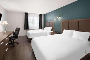 罗贝瓦勒Travelodge by Wyndham Roberval的有两张床和一张书桌的酒店房间