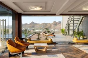 a living room with yellow furniture and a large window at Ramada Encore by Wyndham Udaipur Roopnagar in Udaipur