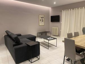 a living room with a black couch and a table at Alyzia Apartment in Xylokastro