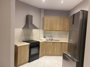 a kitchen with wooden cabinets and a stainless steel refrigerator at Alyzia Apartment in Xylokastro