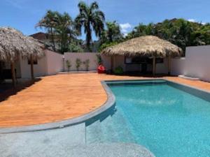 a swimming pool with two straw umbrellas next to a building at EL Cielo de Cana in Las Terrenas