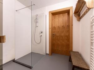 a glass shower door in a bathroom with a bench at Heimelig L in Saalbach-Hinterglemm +25 photos