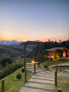 a pathway leading to a house with a sunset in the background at Pousada Chales Joao de Barro in Visconde De Maua