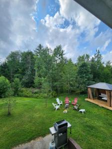 a backyard with a grill and chairs and a gazebo at Backyard Bliss in the White Mountains in Lincoln