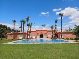 a house with a swimming pool and palm trees at Villa Rayan Marrakech secteur Palmeraie dans Propriété de 2 hectares avec jardin arbres fruitiers in Marrakesh