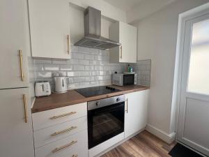 a kitchen with white cabinets and a stove top oven at 2025 Award Winner Liverpool Cherry House - 4 Bedrooms in Liverpool